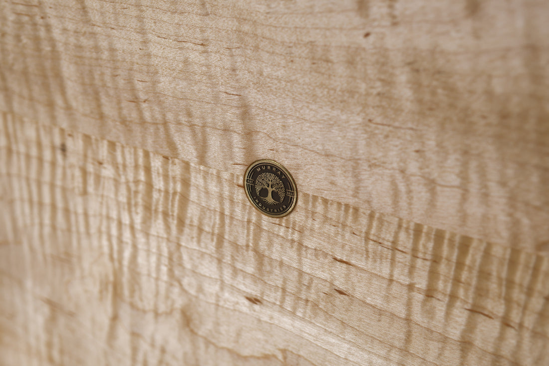 Murray Industries brand medallion inlaid on curly maple — every board carries the shop mark